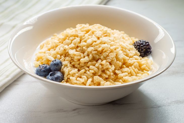Bowl of popped rice breakfast cereal with milk blueberries and raspberries