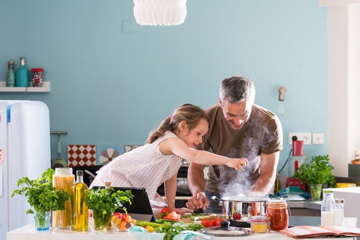 Daddy and his little daughter cooking bolognese sauce for spaghetti in the kitchen