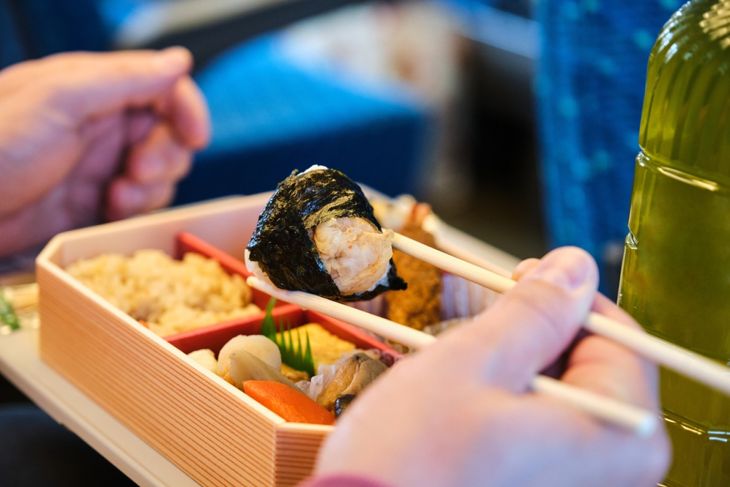 Unrecognizable person eating Japanese Eki Bento, lunch box, on a Shinkansen Train in Japan.