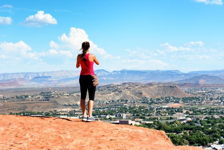 Woman atop the Sugarloaf rock formation overlooking St George, Utah.