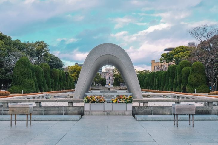 Hiroshima Peace Memorial Park with Cenotaph for A-bomb victims under a partly cloudy sky.