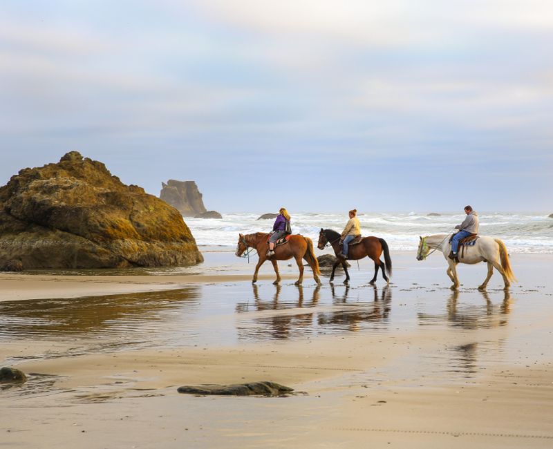 Bandon, Oregon State, USA-April 09, 2016 : Two women and a man riding horses on the bandon beach at sunset.