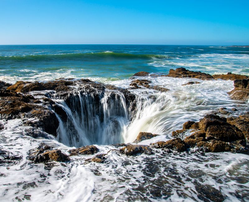 Thor's Well with water cascading into the well on the Oregon coastline.