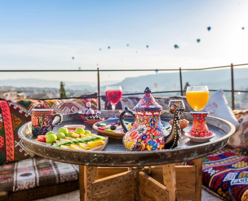 Traditional turkish breakfast with Cappadocia view and flying balloons on the background. Goreme, Turkey.