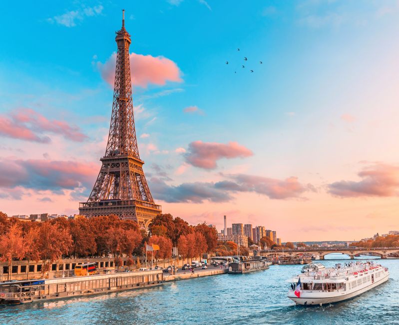 Eiffel tower in the rays of the setting sun on the bank of Seine river with cruise tourist ships