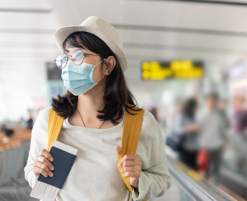 Asian woman wearing protective face mask in international airport.