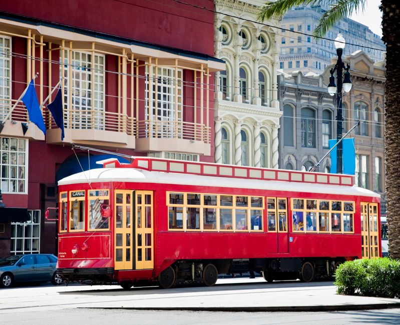 New Orleans Bright Red Streetcar Traveling Amid Palms and Flags