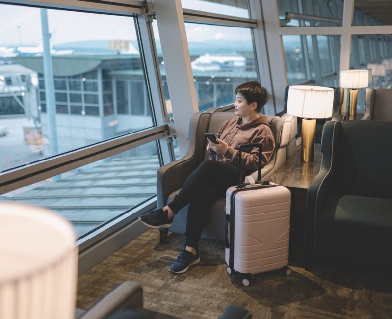Female traveler sitting in an airport lounge overlooking the terminal