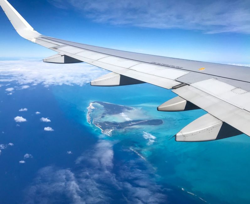 Airplane wing with an island and ocean far below