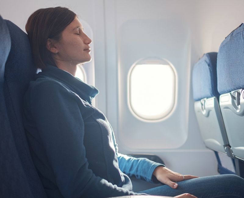 Fear of flying woman in plane sick with stress headache and motion sickness or airsickness. travel with airplane with aerophobia is afraid to fly, sitting on seat of plane.