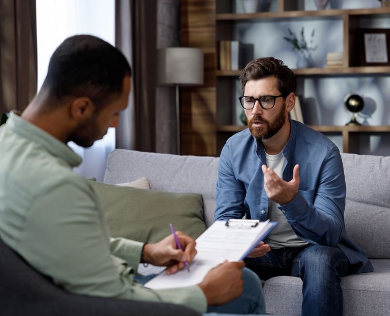 Visit to a psychologist. A man sits on a couch and talks to a psychotherapist. The patient is depressed, apathetic and stressed from problems in his personal life. Help of a psychologist.