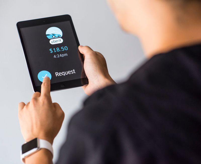 Young man holds a smart device while using Uber app