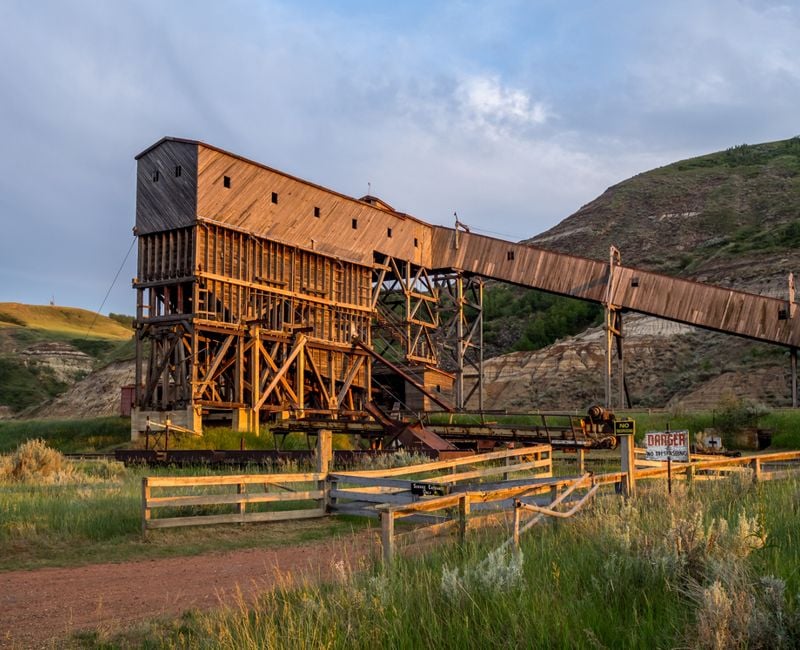 An old and historic coal mine building in the badlands region near Drumheller Alberta Canada at sunset.
