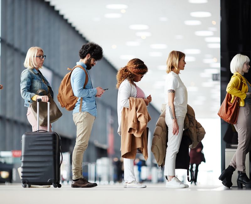 Side view of multiracial people standing in queue to check in in airport hall 
