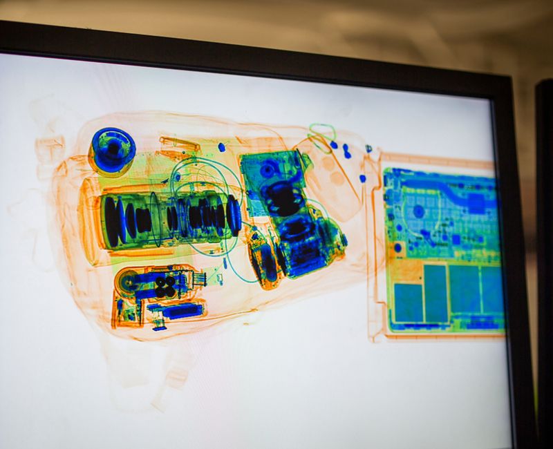 Hand luggage, backpack with camera and lenses and computer being scanned by airport security check x-ray machine. 