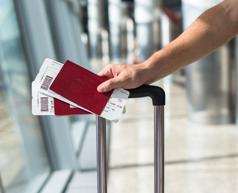 Closeup of man holding passports and boarding pass at airport 