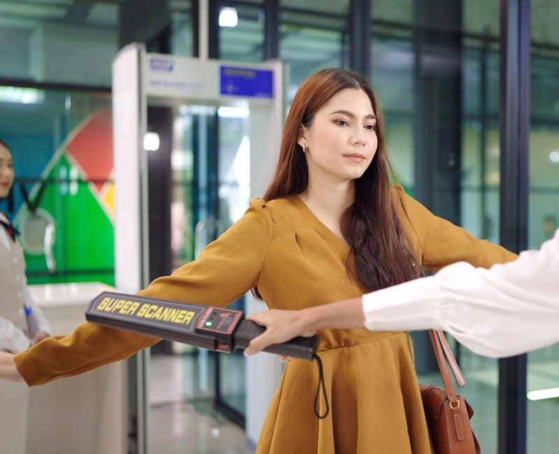 Security agent at airport check in gate with metal detector and scanner to passenger