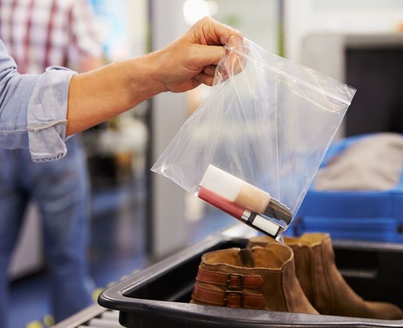 Passenger Puts Liquids Into Bag At Airport Security Check 
