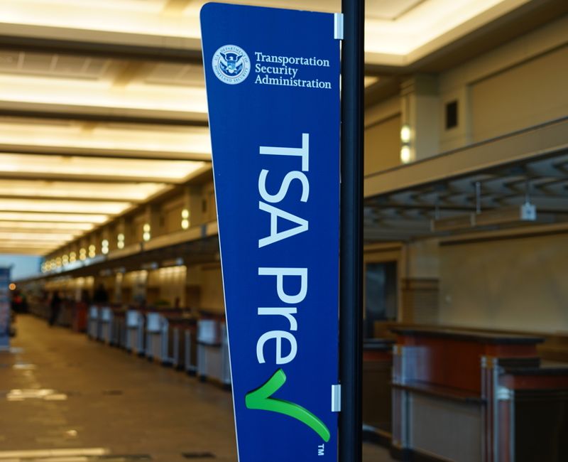 Sign encouraging passengers to register for the time-saving TSA Prec Check program in the United Airlines (UA) terminal