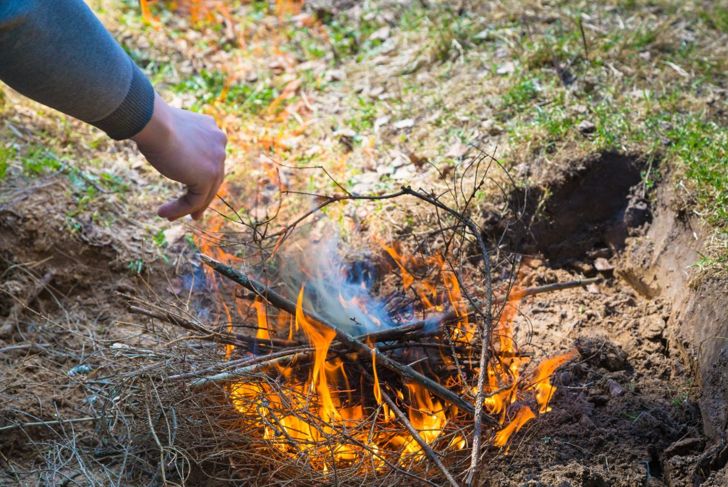 Person prepares a fire pit to use the smoke as a snake repellent.
