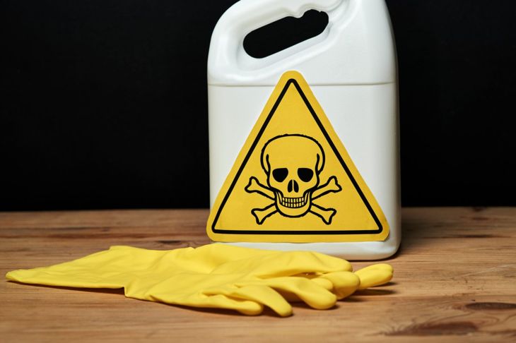 Bottle of snake repellent ammonia sits on a table alongside a pair of household cleaning gloves.