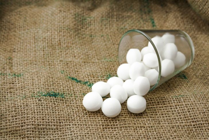 Spilled container of mothballs containing naphthalene for use as a snake repellent.