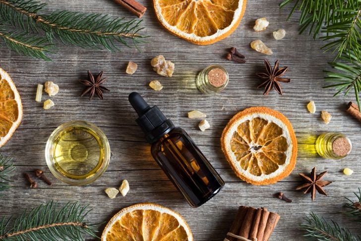 Cinnamon and clove are strewn on a table around a bottle of essential oil with snake repellent properties.