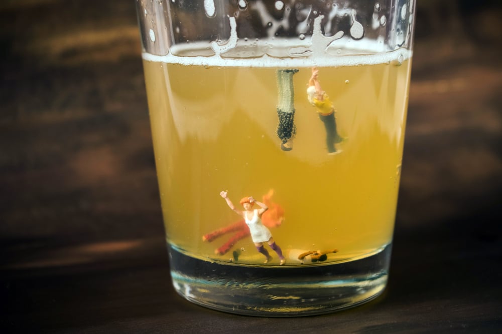 Anonymous, unrecognizable miniature people in a glass of beer